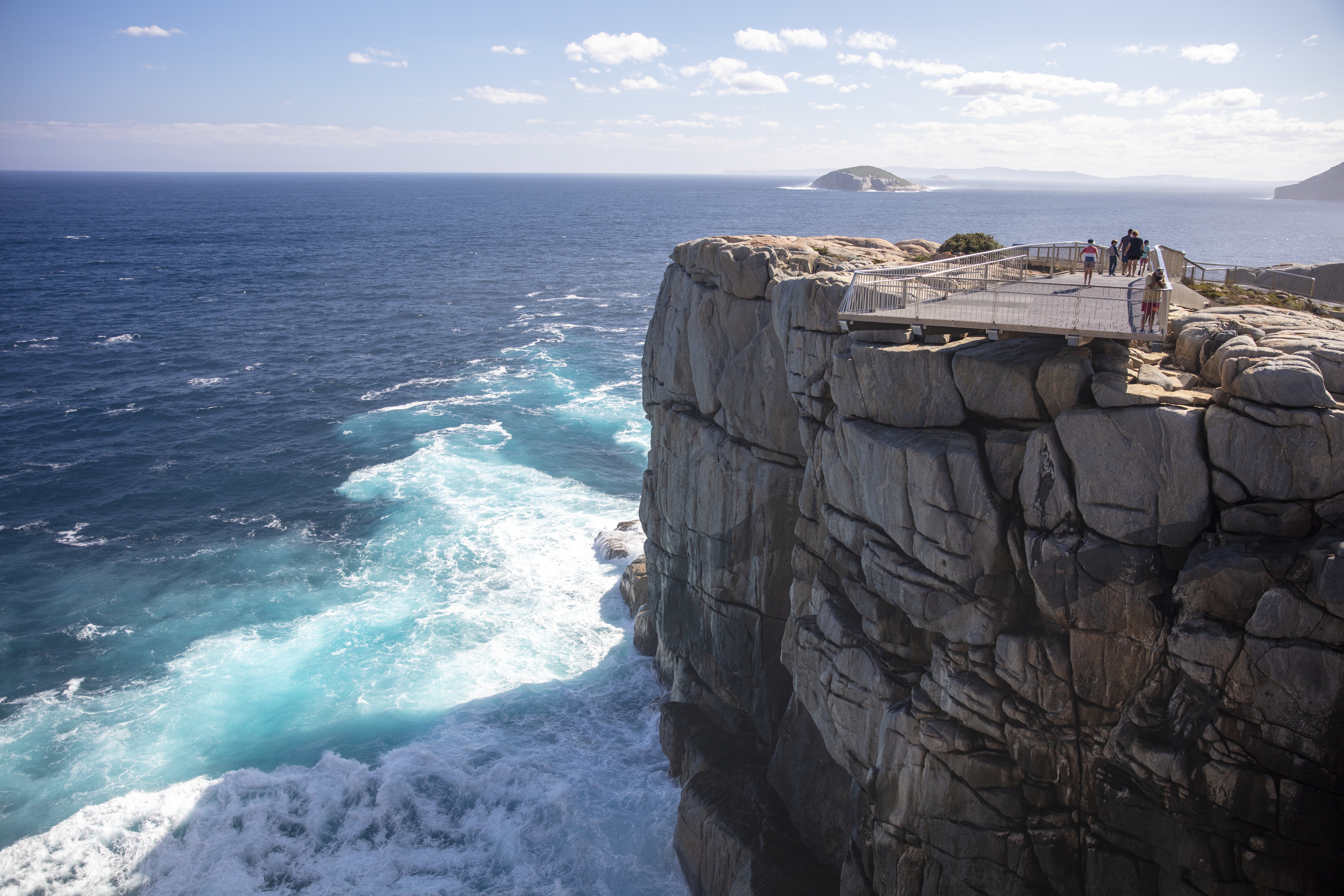 a big granite cliff with huge waves crashingf